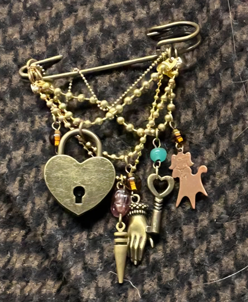 KRT Safety Brooch detail shot showing charms on grey fabric